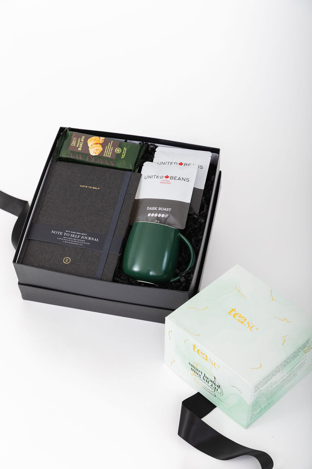 Gift set with a green mug, notebook, and coffee package in a box on a white background.