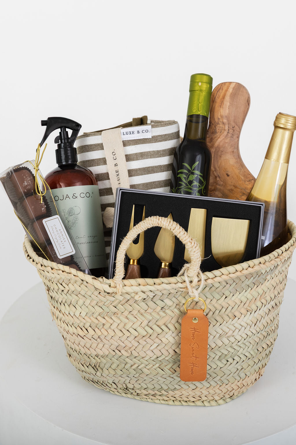 Woven basket with various items including bottles, a book, and a striped bag on a white background